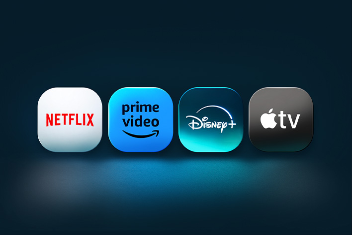 The Netflix, Prime Video, Disney+, and Apple TV app logos stand side-by-side in front of a blue backdrop. 	