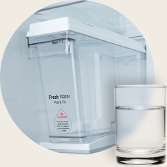 Close-up of LG’s 2007 Non-Plumbing Ice Maker with Pull & Fill water tank and a glass of water placed in front.