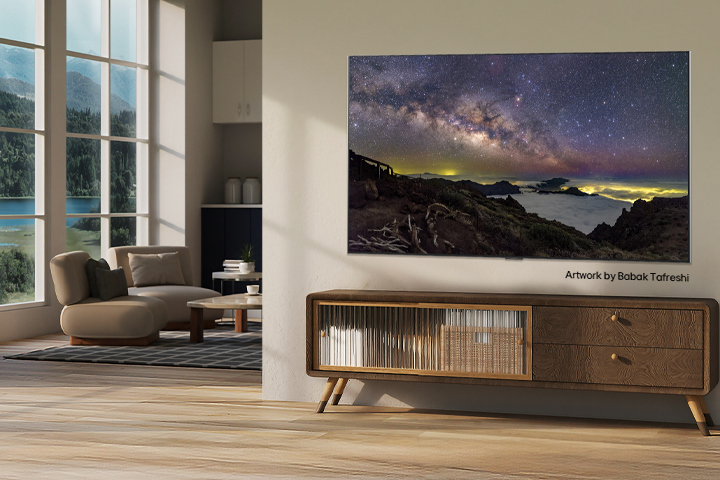 Interior of a countryside home. A huge wall-mounted LG TV is displaying a beautiful natural landscape artwork on its screen. The TV looks like a photograph hung on the wall. 