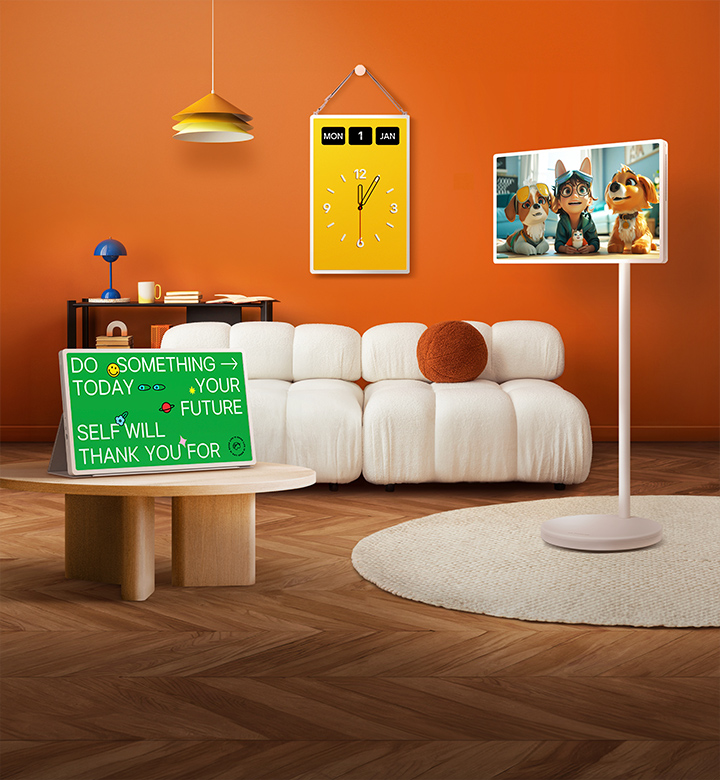 LG StanbyME 2 screens displayed in a modern living room. There is a StanbyME 2 on a stand, one is hung on the wall, and the other is propped up on a table using the folio cover.	