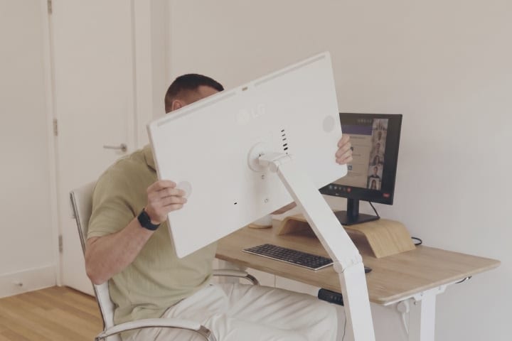 A man sitting on a chair and rotating an LG Smart Monitor Swing screen to a 45-degree angle.