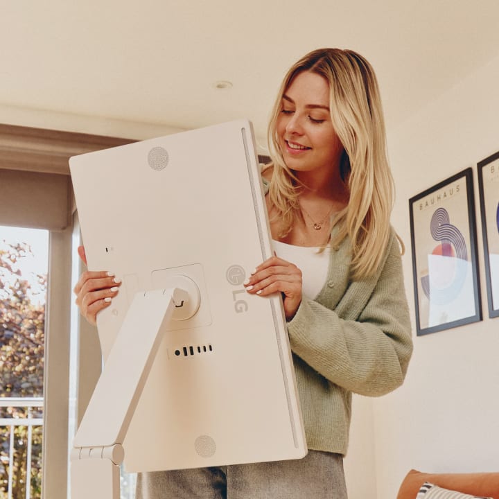 A woman rotating an LG Smart Monitor screen.