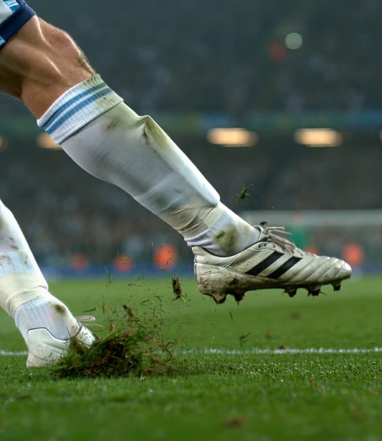 Football player kicking a ball on a grass pitch during a match