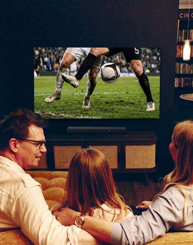 Family watching a football match on a TV from behind