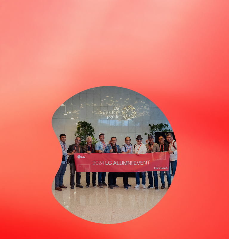 Group of people holding a banner that reads '2024 LG Alumni Event' in front of the LG Science Park. 	