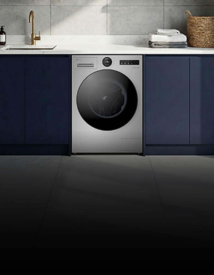 A white front-loading washer sits beneath a wooden shelf, surrounded by neatly placed towels and decor.