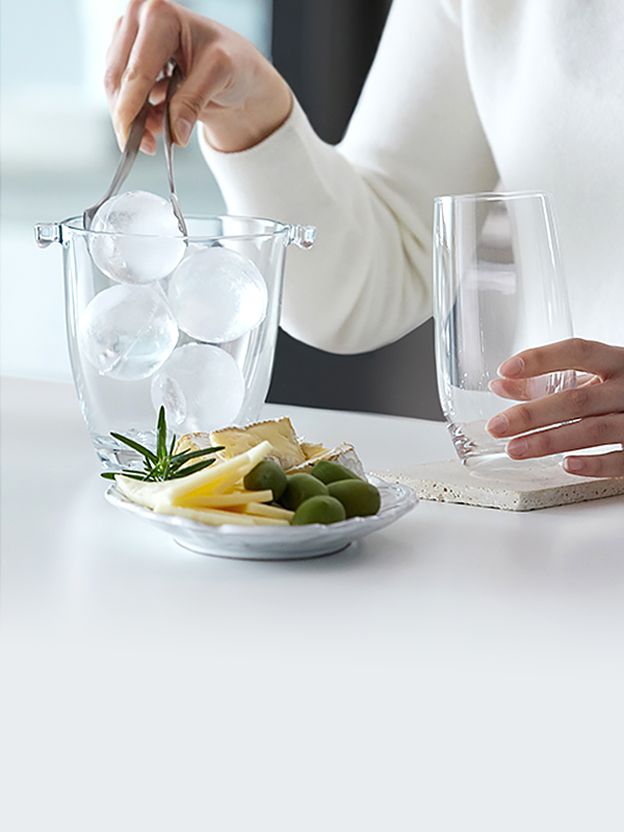 LG refrigerator Craft Ice drawer and a hand placing round ice balls into a glass container illustrate slow-melting spherical ice for drinks.