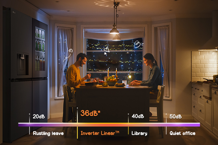 A couple is enjoying a meal in front of a quiet refrigerator.