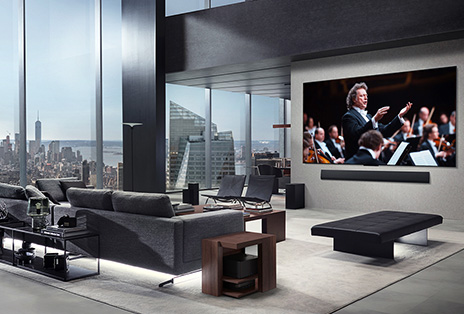 Living room with an LG True Wireless TV and LG Soundbar that's wall-mounted. The Zero Connect Box is barely seen under a side table by the couch, showing how it can easily be placed anywhere. The whole living room's layout is visually neat and tidy. 