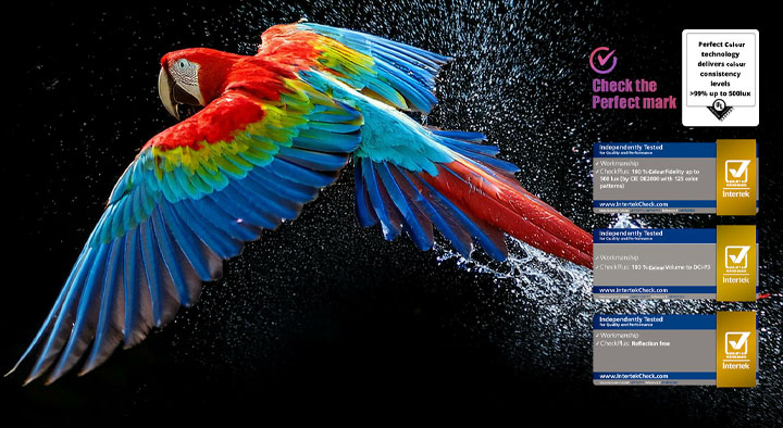 Colourful parrot in ultra-high definition against a black background. Water drops are suspended in the air all around it. The image showcases Perfect Color as each different hue on the parrot's body is vibrant and vivid. The dark background with the detailed water splashes also highlights how the screen is reflection-free. Different logo certifications from UL and Intertek are visible. These refer to its 100% Color Fidelity, 100% Color Volume, and reflection-free claim. Text is also visible, check the Perfect Color certification mark.