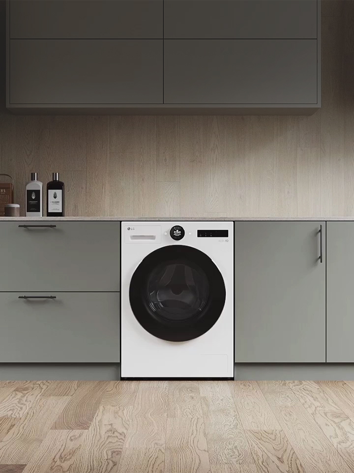 LG front load washing machine, white with black door, integrated in modern grey kitchen cabinets.