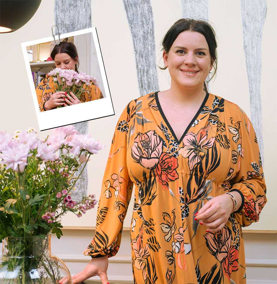 It's an image of a woman looking straight ahead next to a pink flower.
