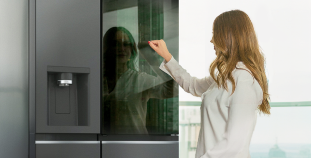 A woman knocking on the glass door of LG InstaView American refrigerator to see the inside of the fridge.