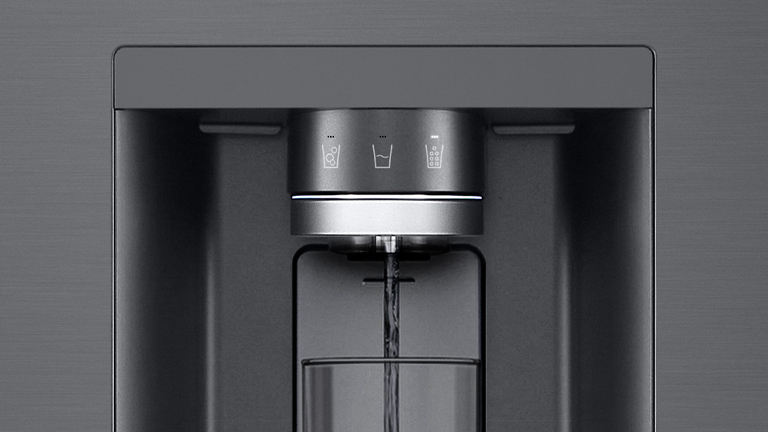 LG refrigerator water dispenser, grey finish, dispensing water into a glass below.