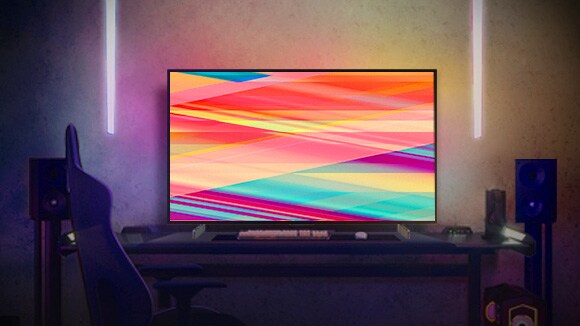 صورة يظهر بها تلفزيون OLED C2 من إل جي في غرفة مضاءة بدفء في الليل مع أرائك، والكثير من الوسائد، ومصباح، وطاولة جانبية ومجموعة من النباتات.