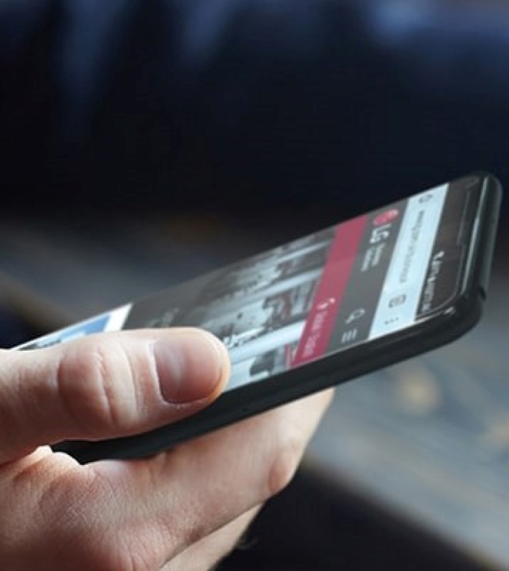 An image of a man holding a smartphone with LG web page on the screen.