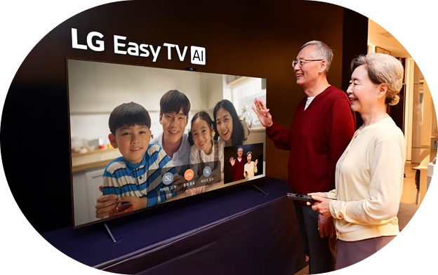 An image of the LG Easy TV AI product. A middle-aged man and woman stand side by side in front of the LG Easy TV AI, smiling while looking at the TV screen. The TV screen displays a natural landscape video along with menus for LG Simple Home, Channels, Life Notifications, Photos, and Customer Service, as well as app icons for Netflix, YouTube, and TVING.
