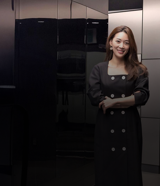 A woman standing and smiling in front of a modern black built-in kitchen