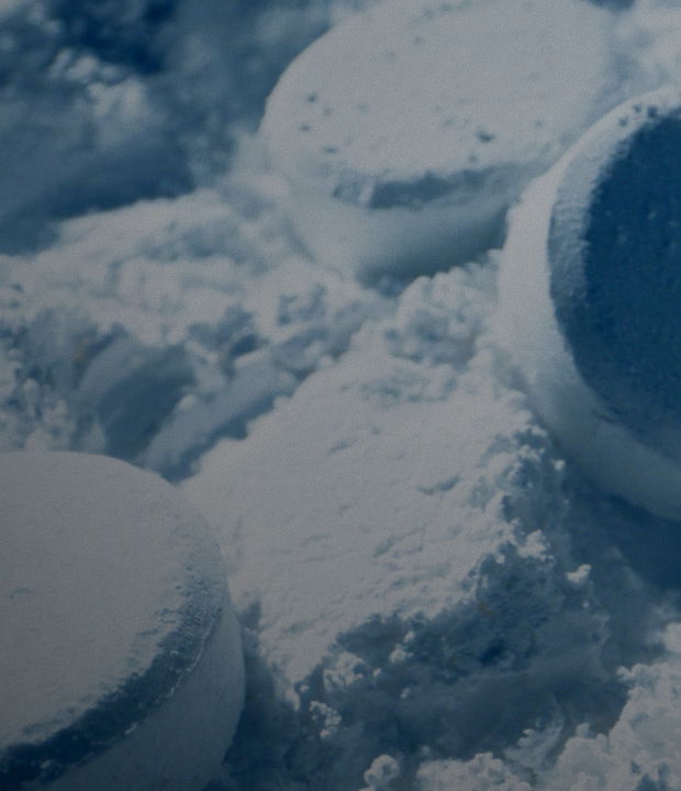 Close-up of circular LG Mineral Wash™ tablets resting on a bed of fine white powder, illustrating deep cleaning mineral technology.
