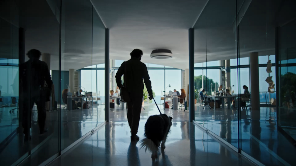 A man holding a dog leash heads to an office.
